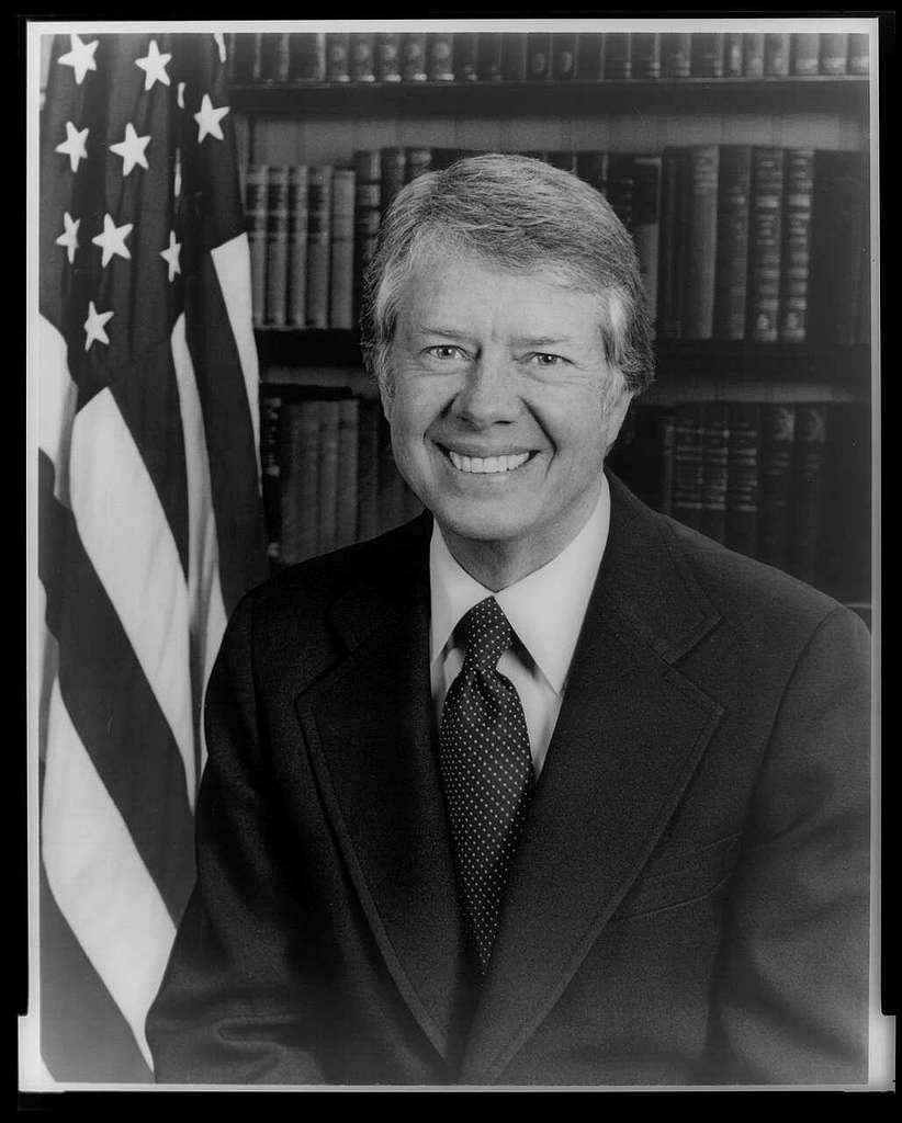 jimmy-carter-head-and-shoulders-portrait-facing-front-next-to-an-american-flag-378081-1024