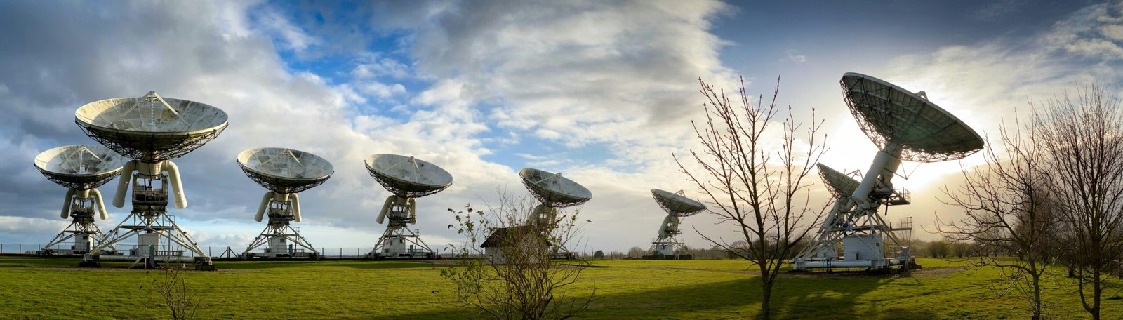 white satellite dish on green grass field under blue sky and white clouds during daytime